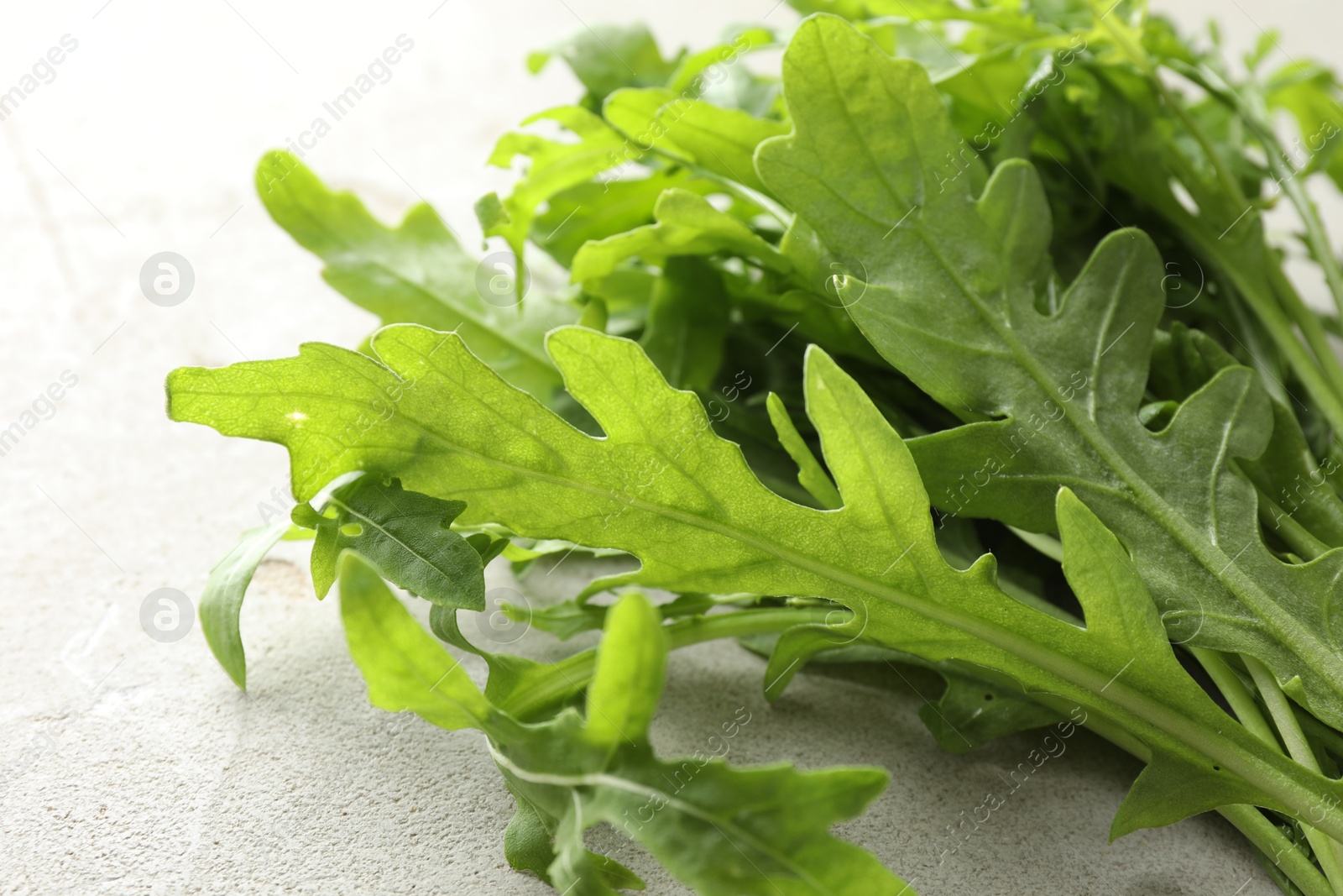 Photo of Many fresh arugula leaves on grey textured table, closeup