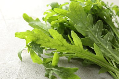 Photo of Many fresh arugula leaves on grey textured table, closeup