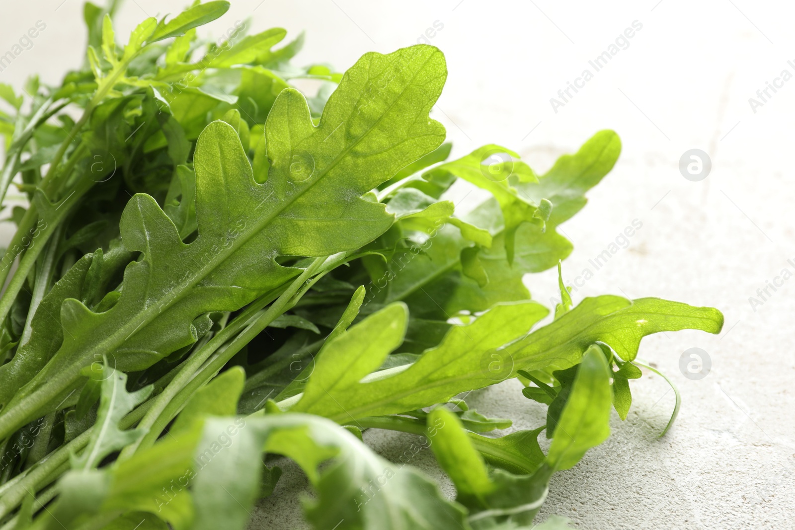 Photo of Many fresh arugula leaves on grey textured table, closeup