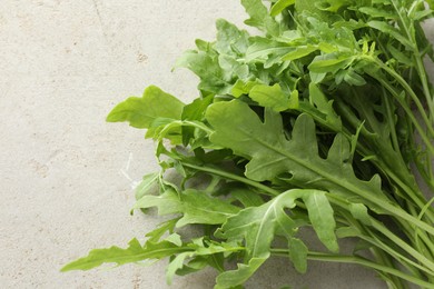 Photo of Many fresh arugula leaves on grey textured table, top view. Space for text