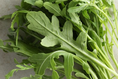 Photo of Many fresh arugula leaves on grey textured table, above view