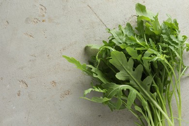 Photo of Many fresh arugula leaves on grey textured table, top view. Space for text