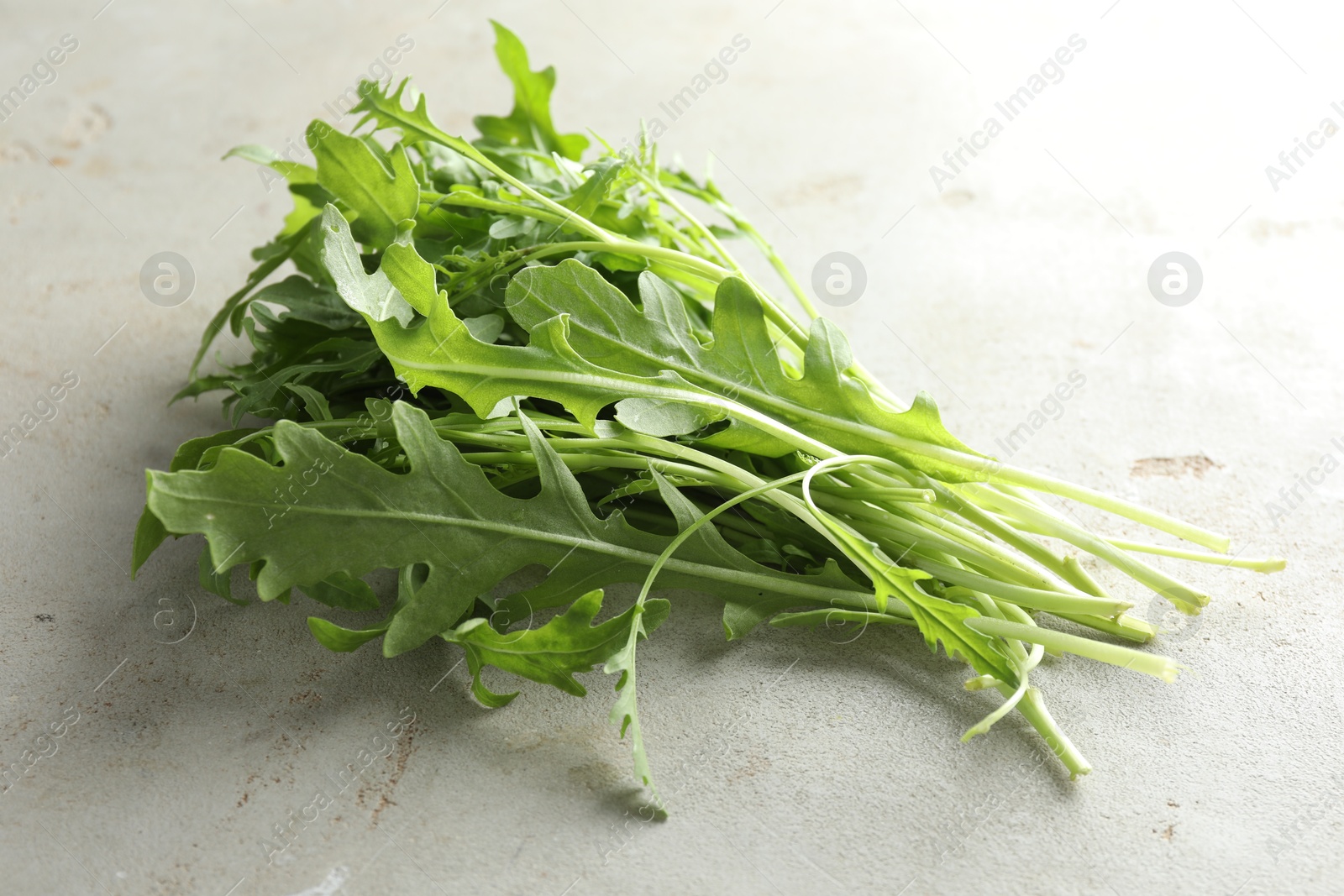 Photo of Many fresh arugula leaves on grey textured table