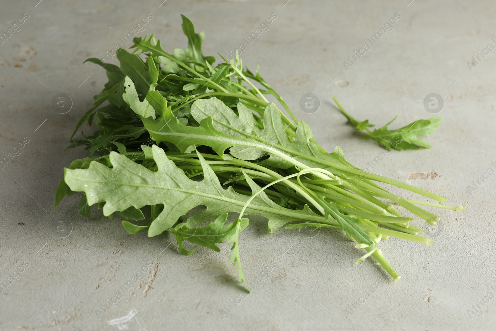 Photo of Many fresh arugula leaves on grey textured table