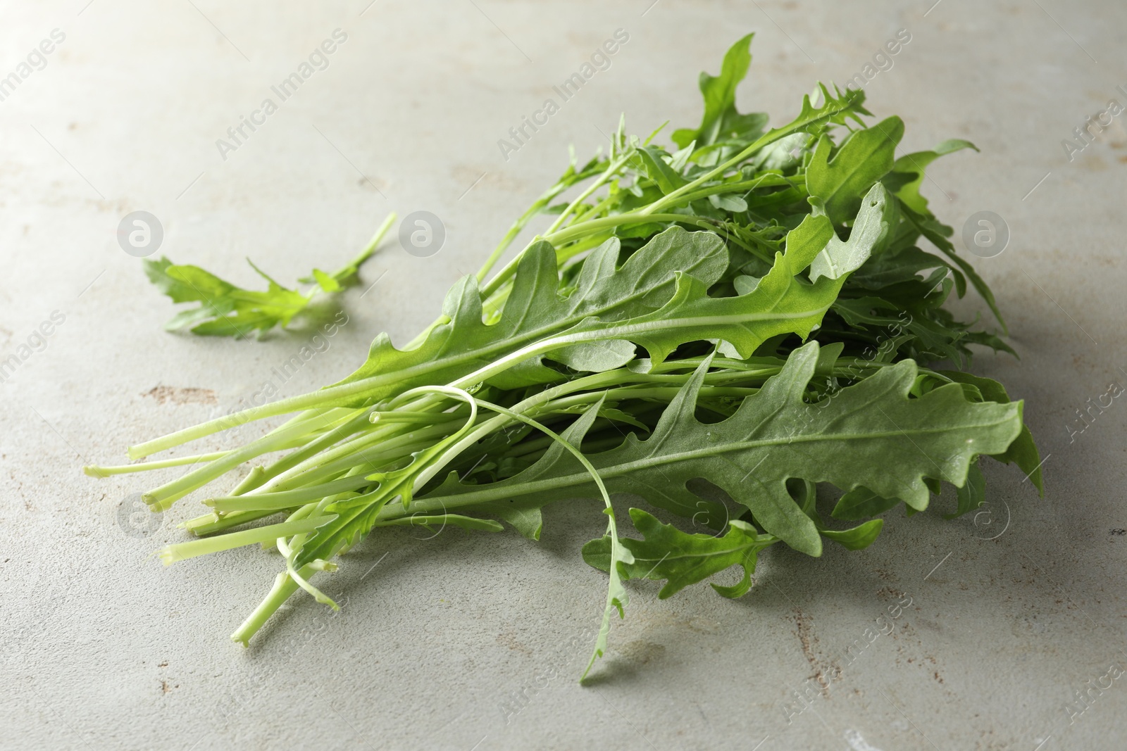 Photo of Many fresh arugula leaves on grey textured table