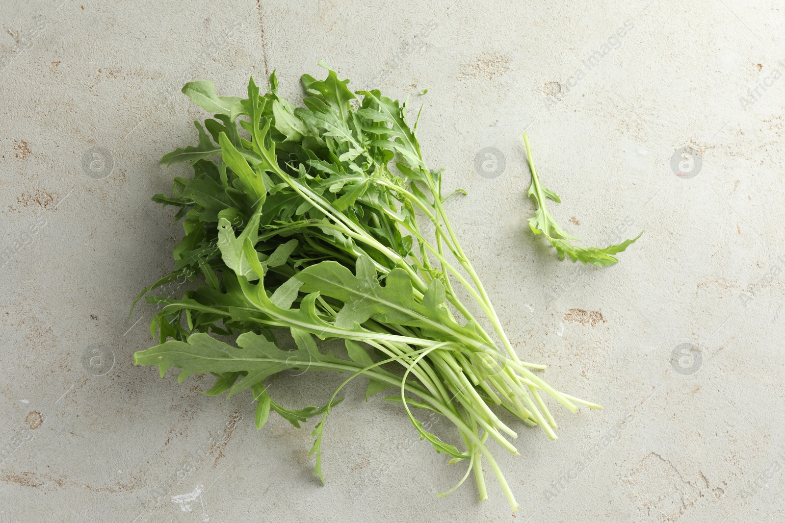 Photo of Many fresh arugula leaves on grey textured table, top view