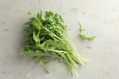 Photo of Many fresh arugula leaves on grey textured table, top view