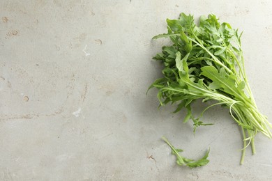 Photo of Many fresh arugula leaves on grey textured table, top view. Space for text