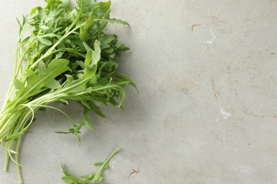 Photo of Many fresh arugula leaves on grey textured table, top view. Space for text