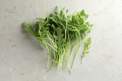 Photo of Many fresh arugula leaves on grey textured table, top view