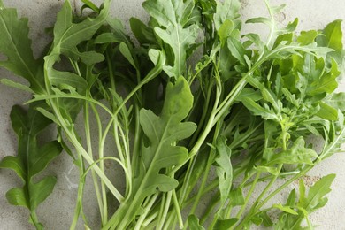 Photo of Many fresh arugula leaves on grey textured table, top view