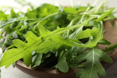 Photo of Many fresh arugula leaves in bowl on table, closeup