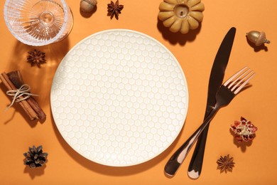 Beautiful table setting with autumn decor on orange background, flat lay