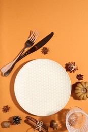 Beautiful table setting with autumn decor on orange background, flat lay