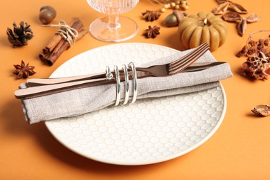 Beautiful table setting with autumn decor on orange background, closeup