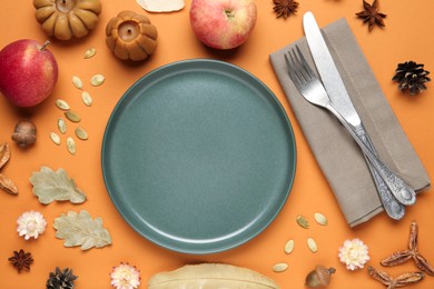 Beautiful table setting with autumn decor on orange background, flat lay