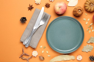 Beautiful table setting with autumn decor on orange background, flat lay