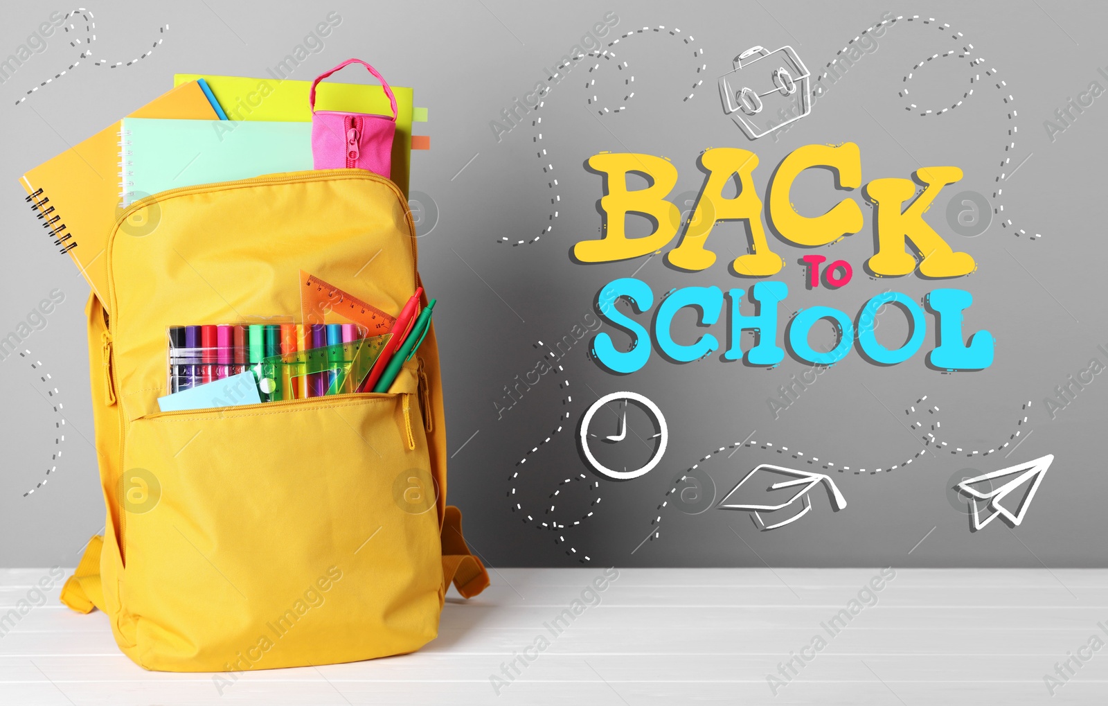 Image of Backpack with stationery on desk against grey background. Back to school