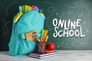 Image of Backpack with stationery on desk near green chalkboard with text Online School