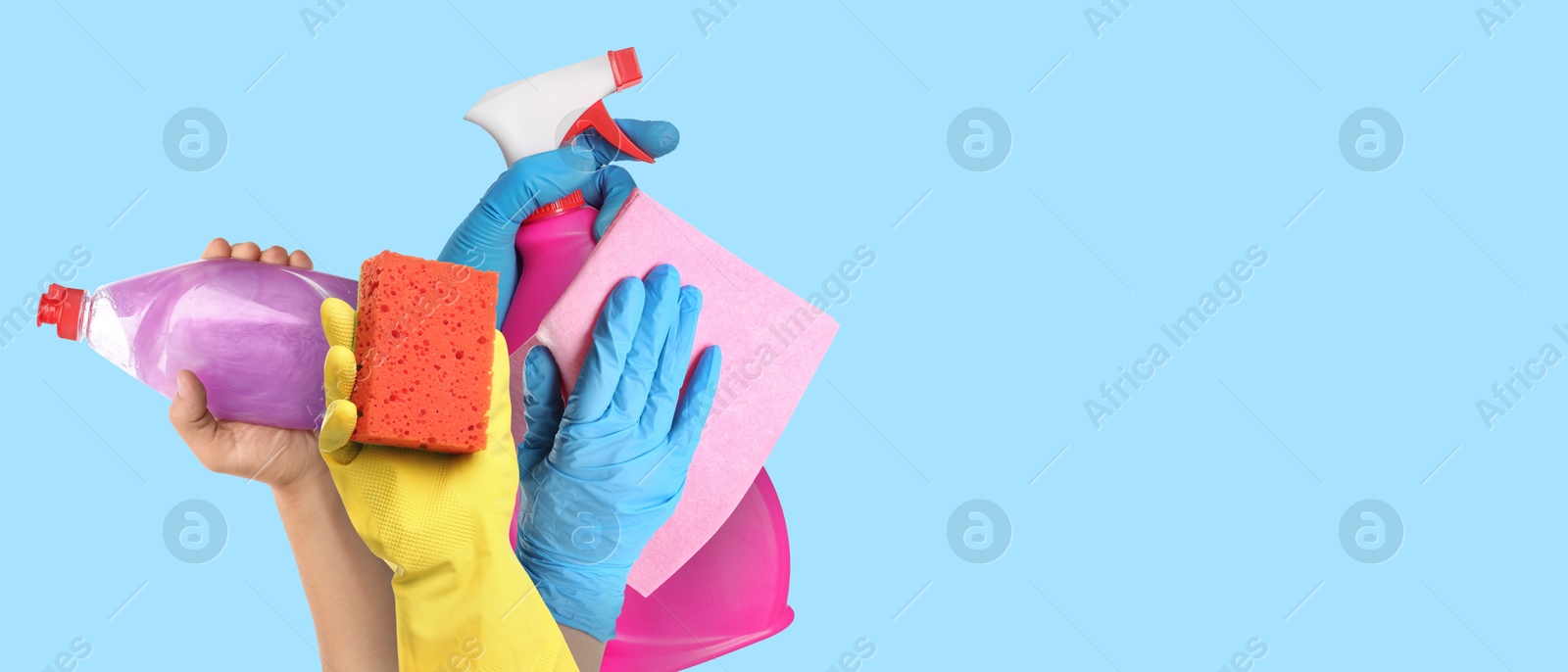 Image of Janitors holding different cleaning supplies on light blue background, closeup. Banner design with space for text