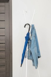 Photo of Blue umbrella and denim jacket on clothing rack in hallway