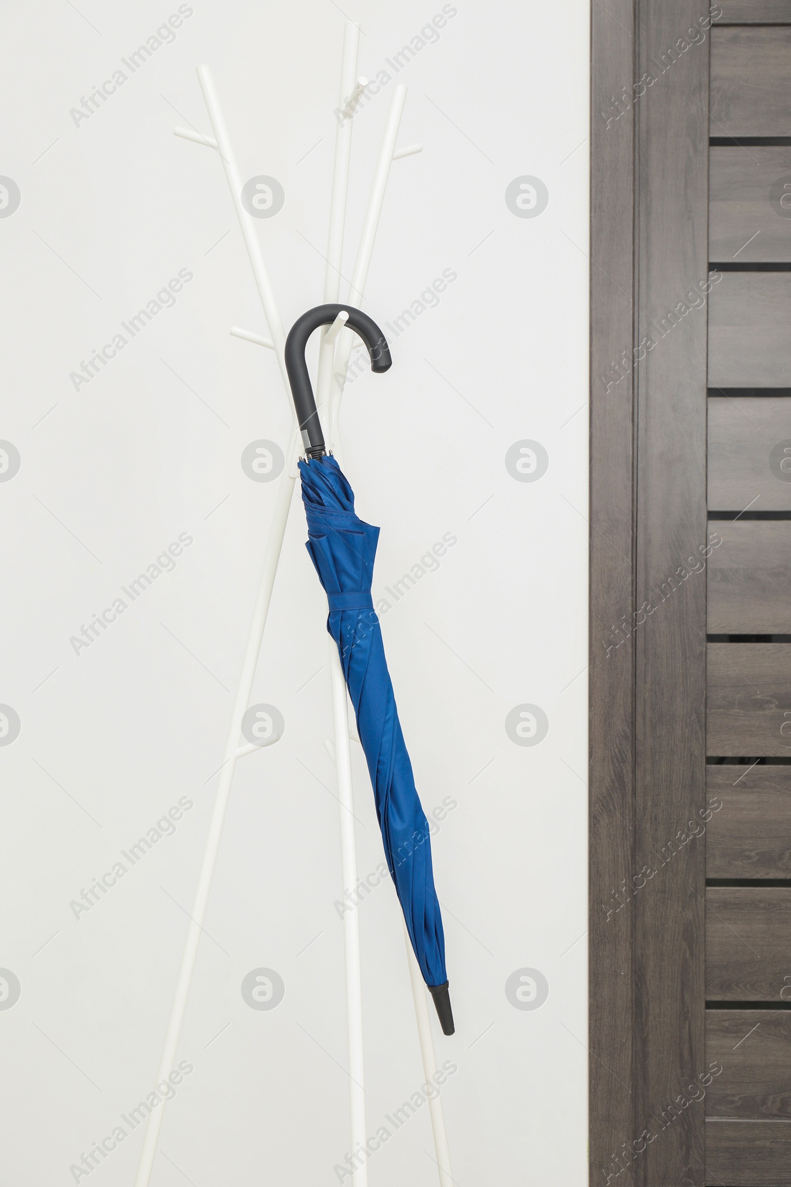 Photo of Blue umbrella on clothing rack in hallway