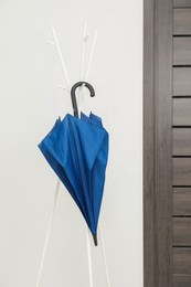 Photo of Blue umbrella on clothing rack in hallway