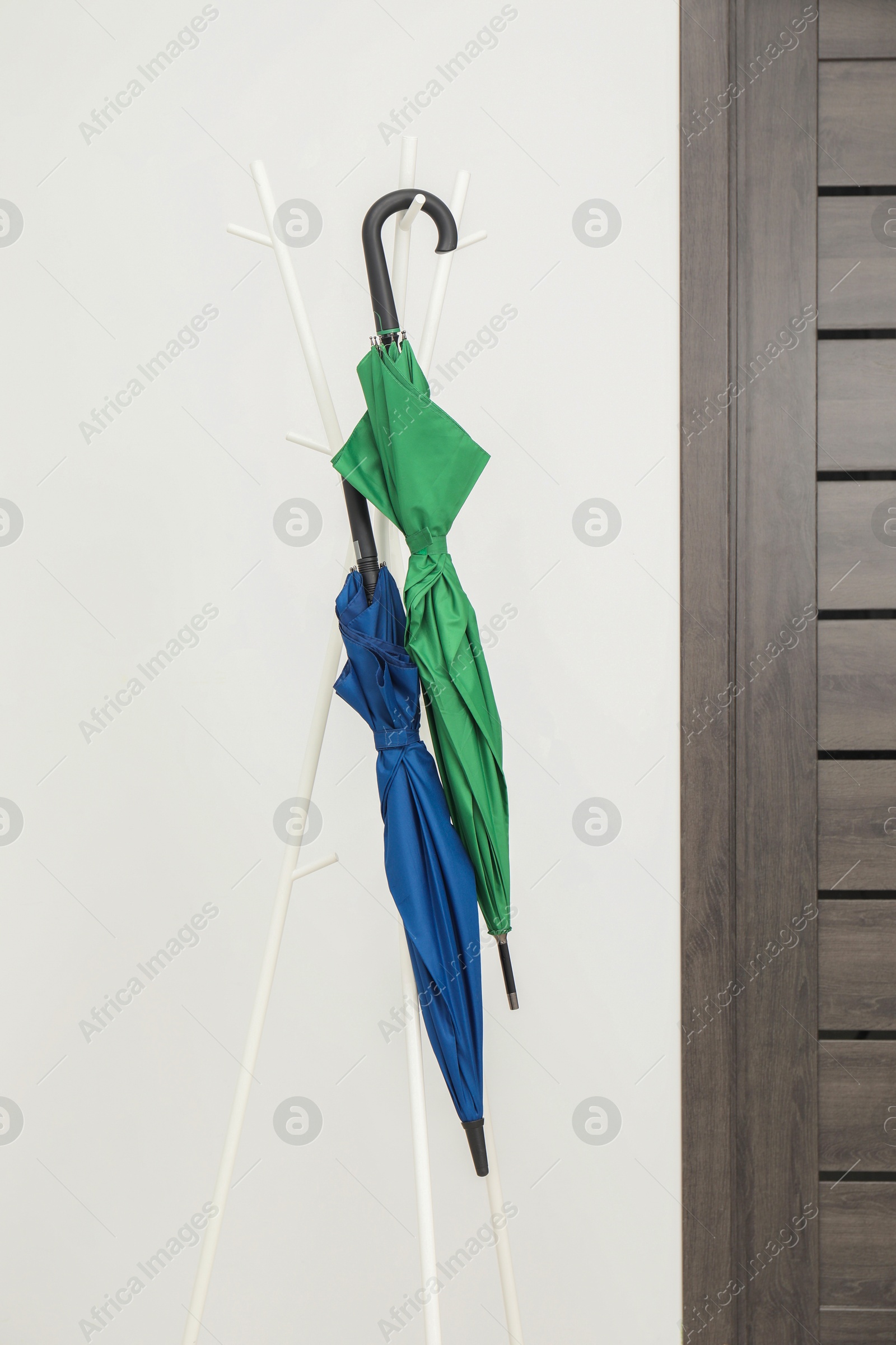 Photo of Colorful umbrellas on clothing rack in hallway