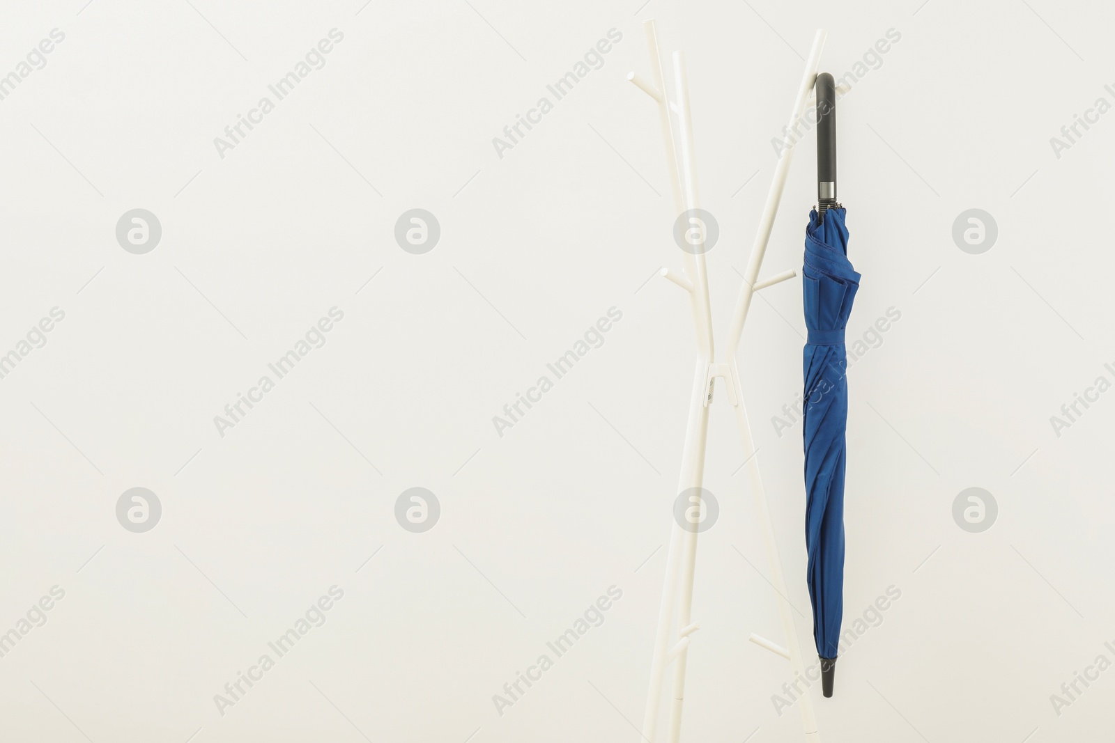 Photo of Blue umbrella on clothing rack against white background, space for text