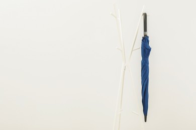 Photo of Blue umbrella on clothing rack against white background, space for text