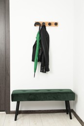 Photo of Green umbrella, leather jacket, rack and ottoman in hallway