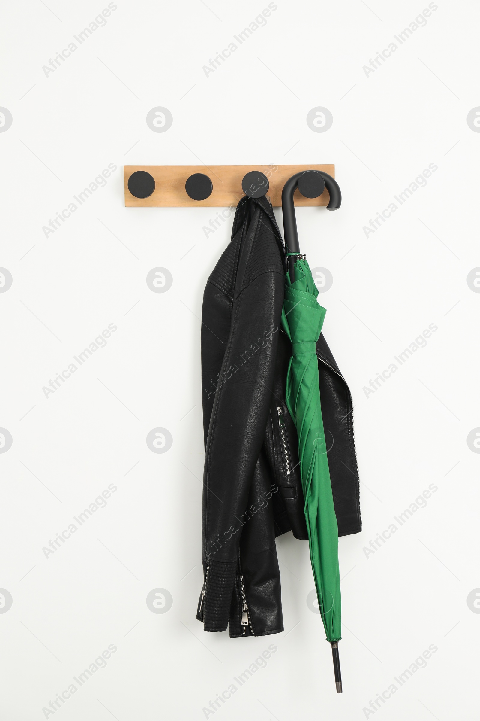 Photo of Green umbrella and leather jacket on rack in hallway