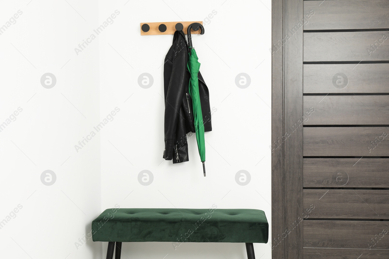 Photo of Green umbrella, leather jacket, rack and ottoman in hallway