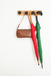 Colorful umbrellas and bag on rack in hallway