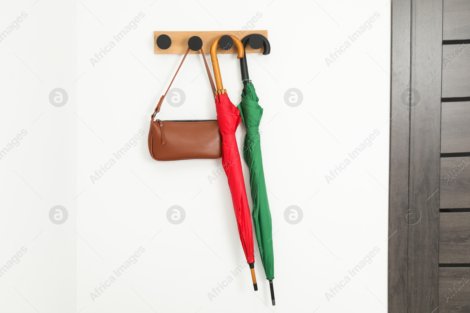 Photo of Colorful umbrellas and bag on rack in hallway