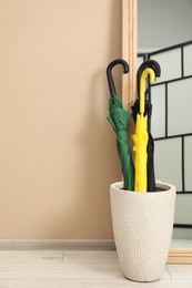 Photo of Colorful umbrellas in holder and mirror indoors