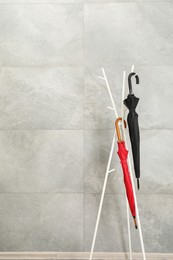 Photo of Colorful umbrellas on rack near gray marble wall