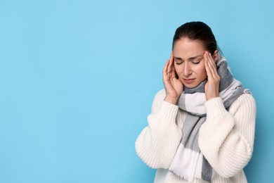 Sick woman suffering from cold symptoms on light blue background, space for text