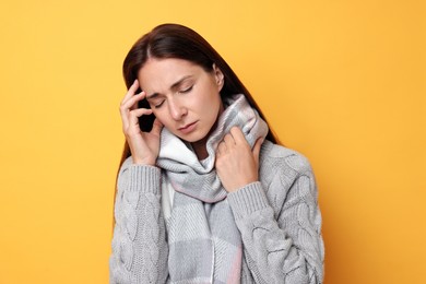 Sick woman suffering from cold symptoms on orange background