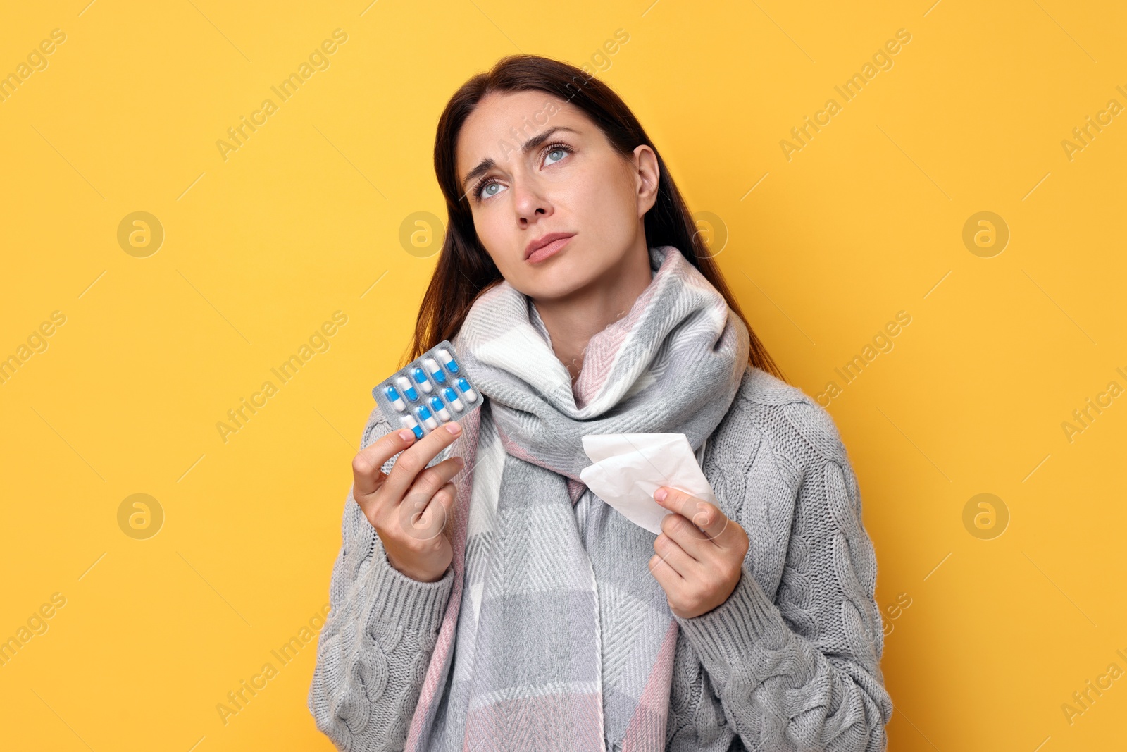 Photo of Sick woman with tissue and pills on orange background. Cold symptoms