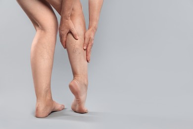 Photo of Woman suffering from varicose veins on grey background, closeup. Space for text