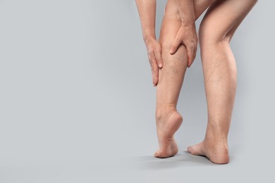 Photo of Woman suffering from varicose veins on grey background, closeup. Space for text