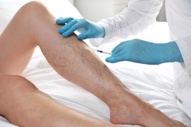 Photo of Varicose veins treatment. Doctor giving injection to patient indoors, closeup