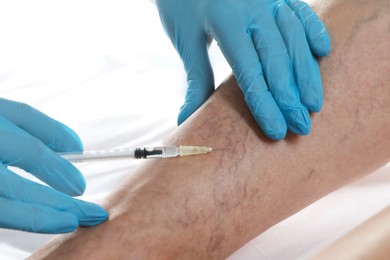 Photo of Varicose veins treatment. Doctor giving injection to patient indoors, closeup