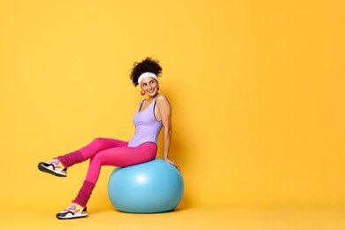 Photo of Aerobics. Woman with fitness ball on orange background