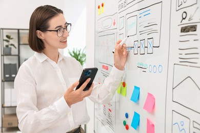 Developing UI design. Woman drawing website wireframe on whiteboard indoors