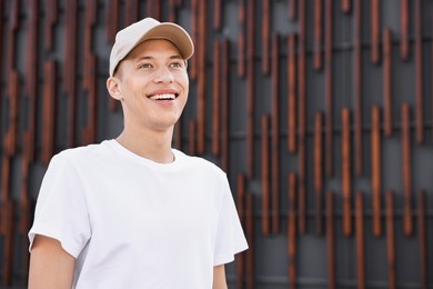 Photo of Smiling man in baseball cap near dark wall. Space for text