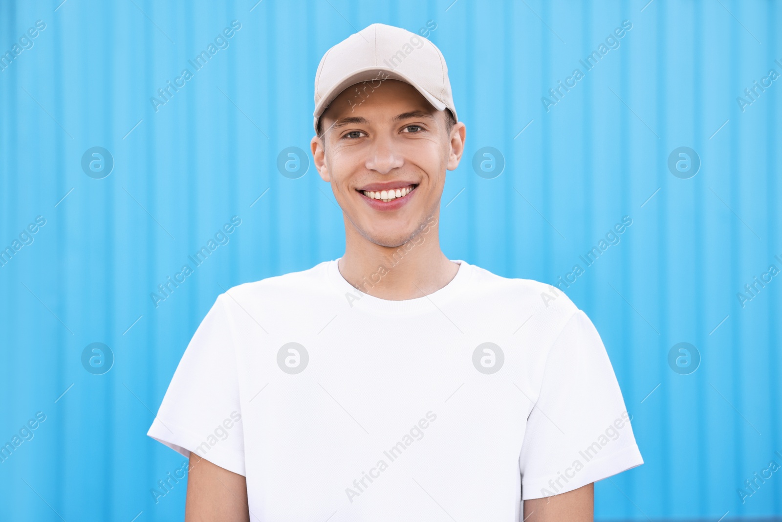 Photo of Portrait of smiling man in baseball cap near light blue wall