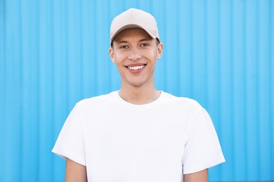 Portrait of smiling man in baseball cap near light blue wall