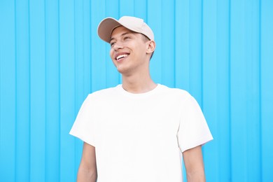 Portrait of smiling man in baseball cap near light blue wall